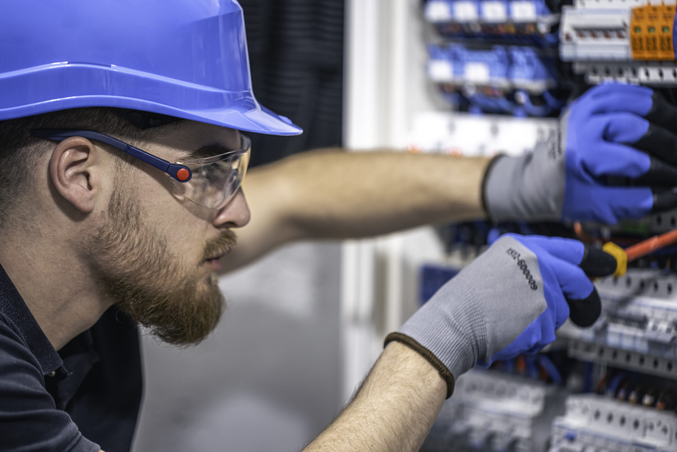 Male electrician works switchboard with electrical connecting cable